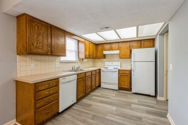 kitchen with sink, light hardwood / wood-style flooring, white appliances, and decorative backsplash