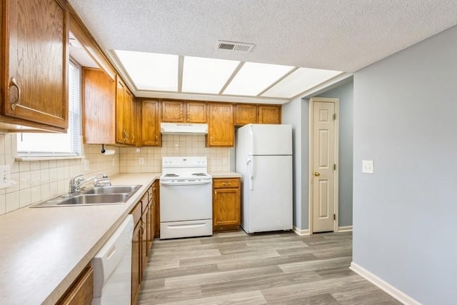 kitchen with sink, decorative backsplash, white appliances, and light hardwood / wood-style flooring