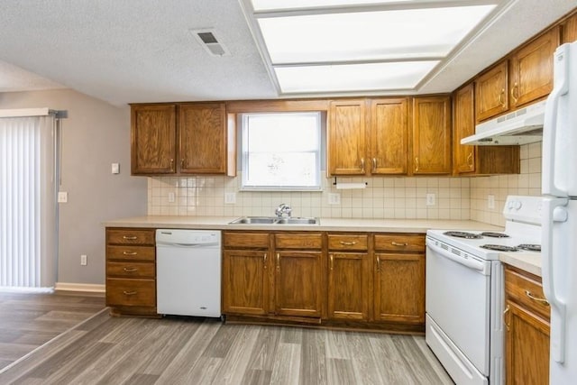 kitchen with tasteful backsplash, sink, white appliances, and light hardwood / wood-style floors