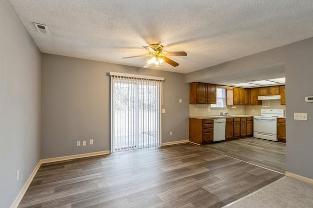 kitchen with dark wood-type flooring, sink, ceiling fan, white appliances, and backsplash