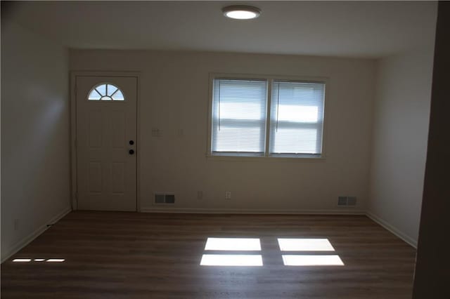 foyer entrance featuring wood finished floors, baseboards, and visible vents