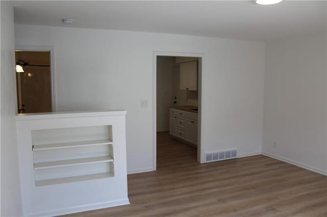 spare room with baseboards, visible vents, and wood finished floors