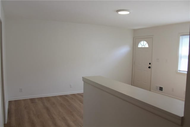 entryway featuring wood finished floors, baseboards, and visible vents