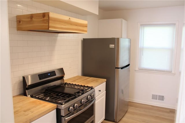 kitchen featuring white cabinetry, visible vents, custom exhaust hood, and appliances with stainless steel finishes