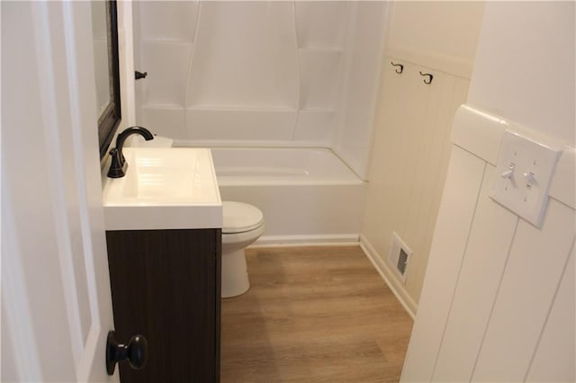 bathroom featuring visible vents, toilet, wood finished floors, vanity, and shower / bathtub combination
