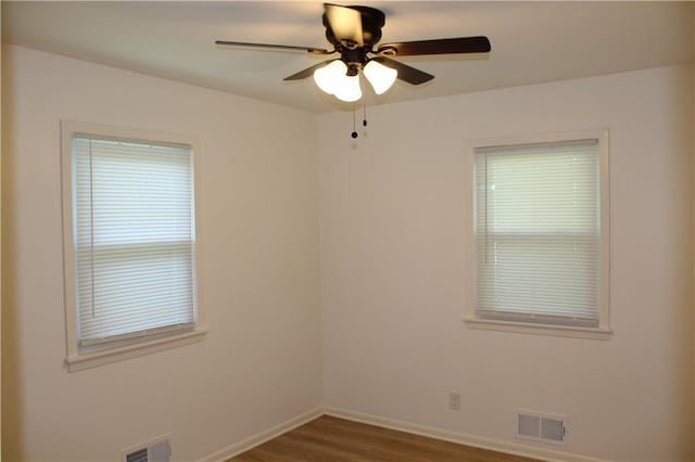 unfurnished room with wood finished floors, baseboards, ceiling fan, and visible vents