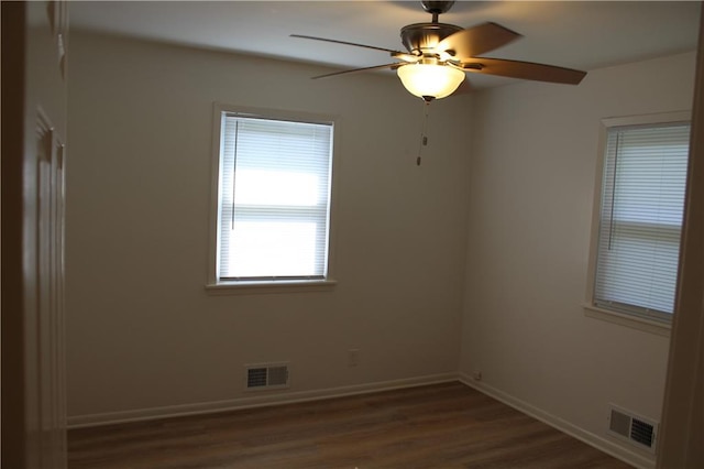 unfurnished room with baseboards, visible vents, a ceiling fan, and dark wood finished floors