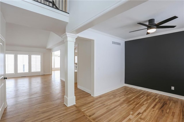 unfurnished room featuring crown molding, light wood-type flooring, a ceiling fan, and ornate columns