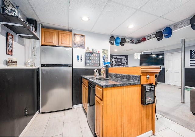 kitchen with stainless steel refrigerator, light colored carpet, and a drop ceiling