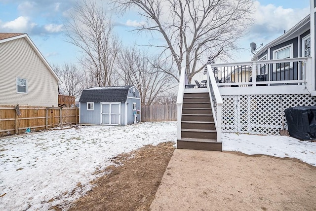 yard covered in snow featuring a storage unit and a wooden deck