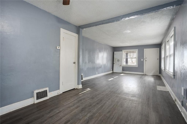 empty room with dark wood-type flooring and a textured ceiling