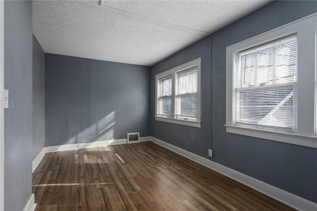 unfurnished room featuring dark hardwood / wood-style flooring and a textured ceiling