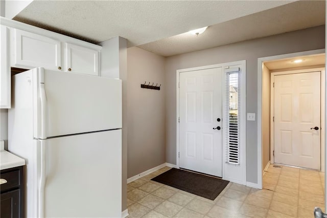 entryway featuring light floors, baseboards, and a textured ceiling