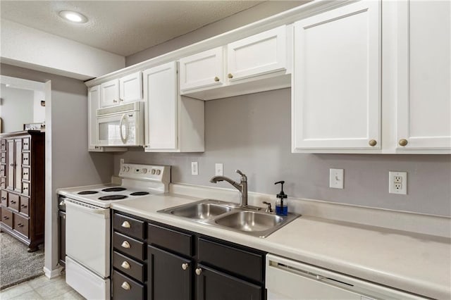 kitchen featuring white appliances, white cabinets, and a sink