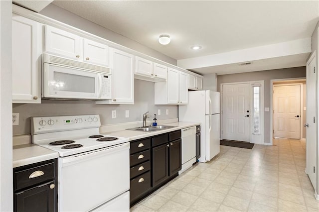 kitchen featuring white appliances, visible vents, white cabinets, and a sink