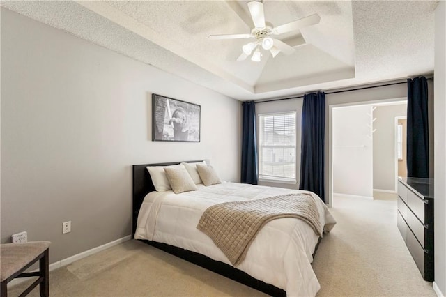 bedroom featuring a textured ceiling, baseboards, a raised ceiling, and light colored carpet