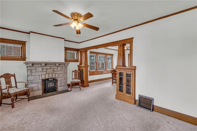 carpeted living room featuring crown molding, ceiling fan, and a wood stove