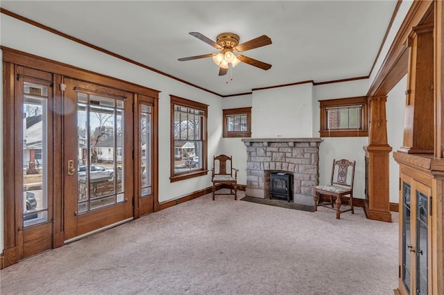 sitting room with crown molding, ceiling fan, a stone fireplace, and light carpet