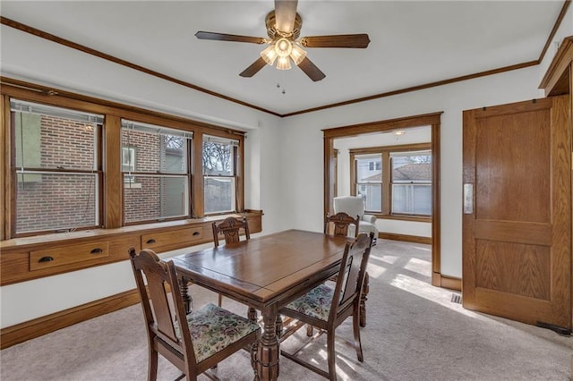 dining area featuring crown molding, light colored carpet, and ceiling fan