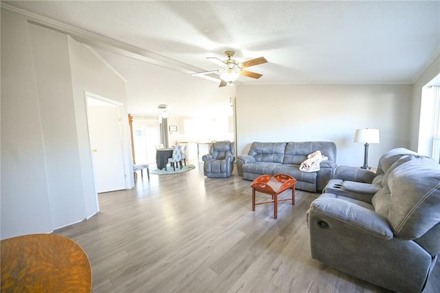 living room with crown molding, wood-type flooring, and ceiling fan