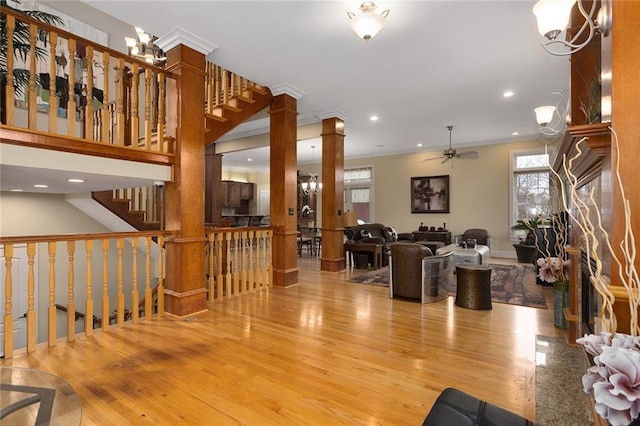 interior space featuring decorative columns, recessed lighting, ornamental molding, wood finished floors, and ceiling fan with notable chandelier