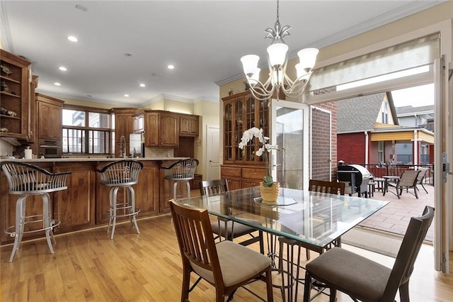 dining area with a chandelier, light wood-style floors, recessed lighting, and crown molding