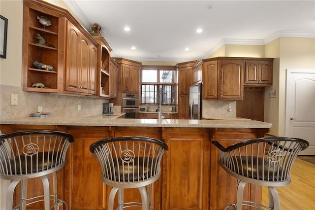 kitchen featuring stainless steel fridge, light stone counters, a peninsula, crown molding, and open shelves