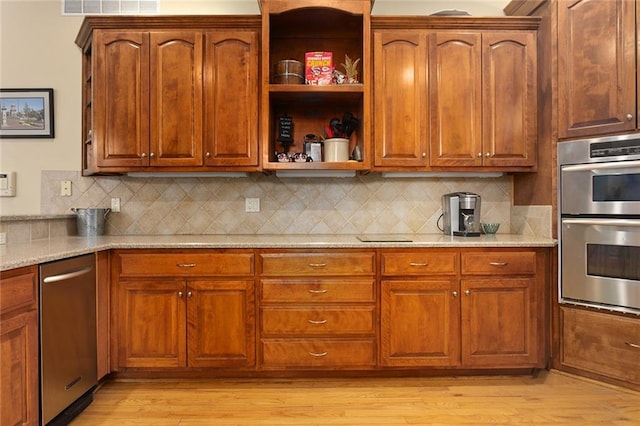 kitchen with double oven, decorative backsplash, light wood finished floors, and light stone counters