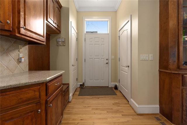 doorway to outside featuring ornamental molding, light wood-style floors, and baseboards