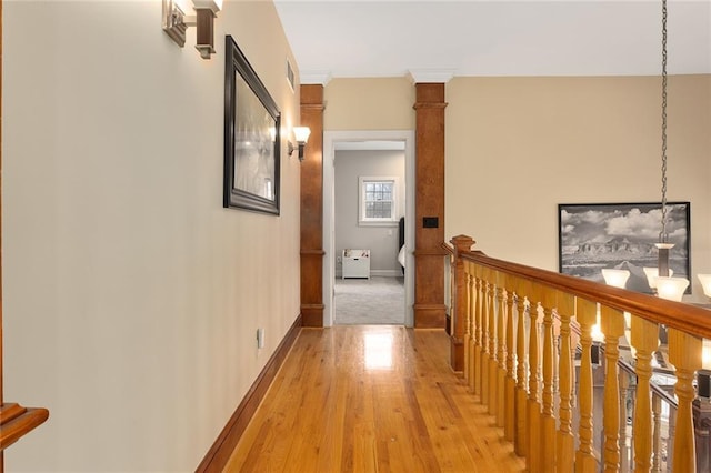 corridor featuring light wood-style flooring, an upstairs landing, and baseboards