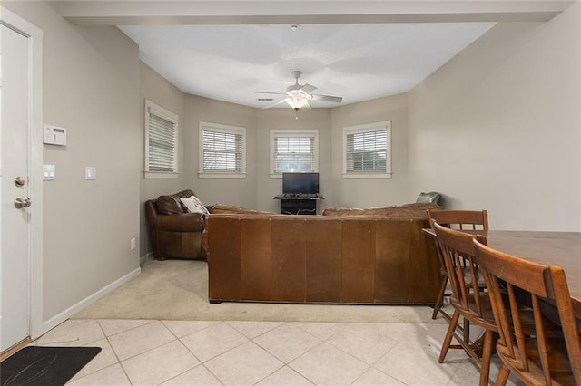 living room featuring ceiling fan, light tile patterned flooring, light colored carpet, and baseboards