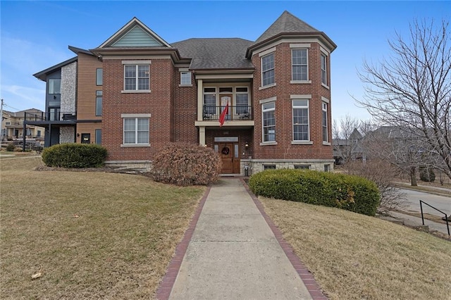 view of front of house with a shingled roof, a front lawn, and brick siding