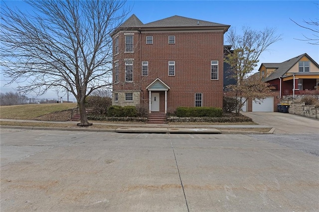 view of front of home with a garage, concrete driveway, and brick siding