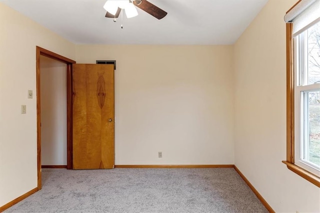 unfurnished room featuring ceiling fan, light carpet, and a wealth of natural light