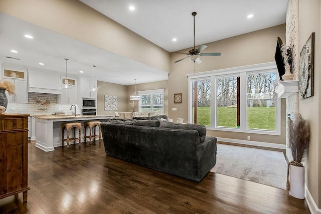 living room featuring sink, dark wood-type flooring, and ceiling fan