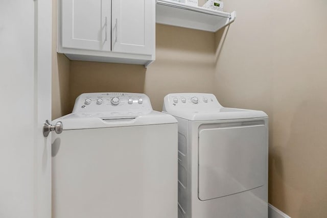 clothes washing area with cabinets and independent washer and dryer