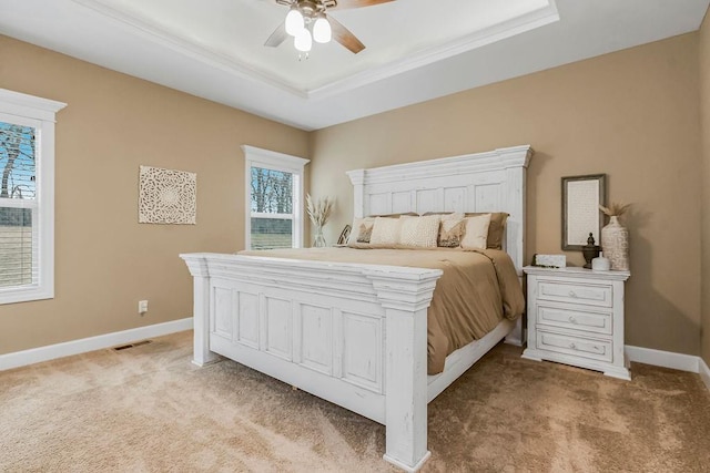 bedroom featuring light colored carpet, a raised ceiling, and ceiling fan