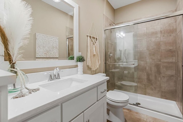 bathroom with vanity, toilet, a shower with shower door, and tile patterned flooring