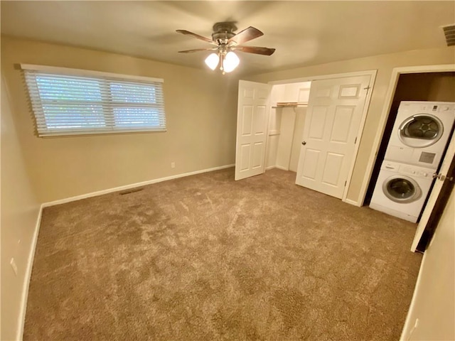 unfurnished bedroom featuring ceiling fan, stacked washer and dryer, a closet, and light carpet