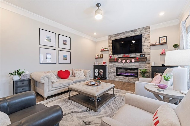 living room featuring crown molding, a stone fireplace, and light wood-type flooring