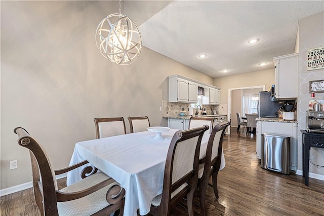 dining area with dark wood-type flooring, an inviting chandelier, and sink