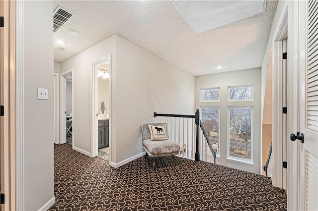 hall with a textured ceiling and carpet