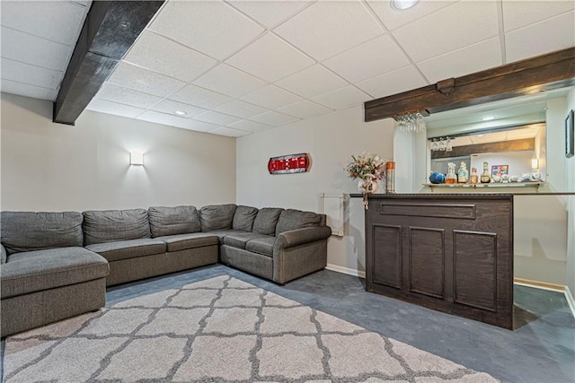 living room featuring beamed ceiling, a paneled ceiling, bar area, and concrete floors