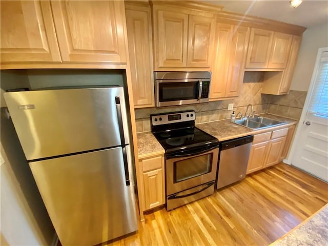 kitchen featuring stainless steel appliances, sink, light brown cabinetry, and light hardwood / wood-style floors