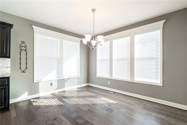 unfurnished dining area featuring an inviting chandelier and dark hardwood / wood-style floors