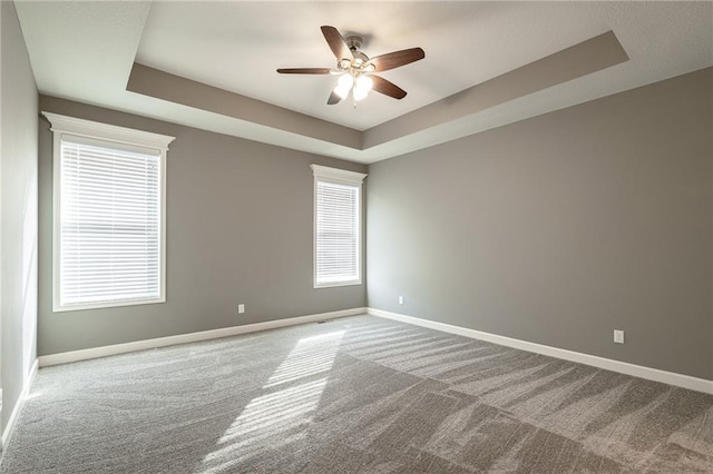 carpeted empty room featuring a tray ceiling and ceiling fan