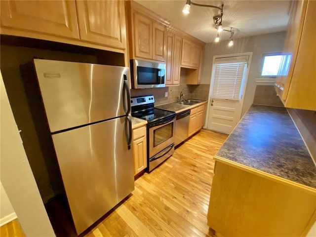 kitchen with tasteful backsplash, sink, stainless steel appliances, light brown cabinets, and light wood-type flooring