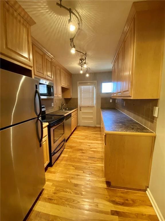 kitchen featuring appliances with stainless steel finishes, light brown cabinetry, decorative backsplash, and light wood-type flooring