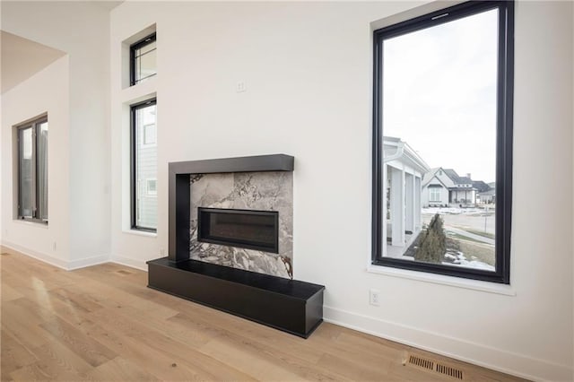 living room with a wealth of natural light, a fireplace, and light hardwood / wood-style flooring