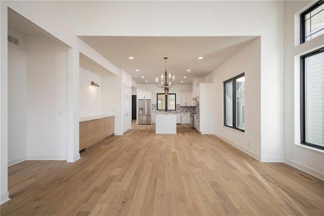 unfurnished living room with a notable chandelier and light hardwood / wood-style floors